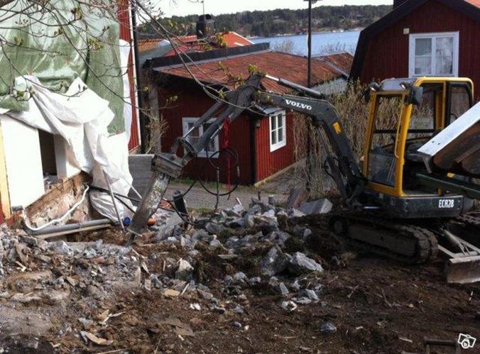 CFS Bygg Mark Dränering Dalarö Haninge. Rivning gjuten betong grund sommarhus med grävmaskin utrustad med hydraulhammare